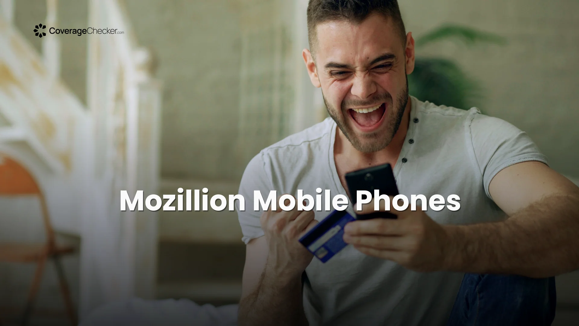 Happy man using phone and credit card indoors, expressing joy and excitement.